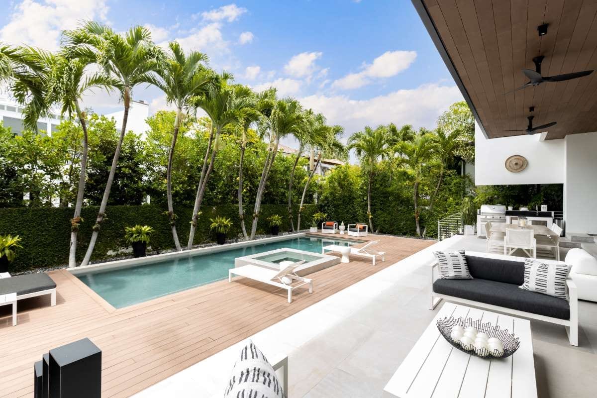 Modern backyard with swimming pool, artificial grass, stone path, trees, and chairs
