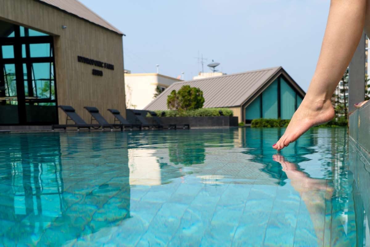 Person testing pool water with a foot before swimming