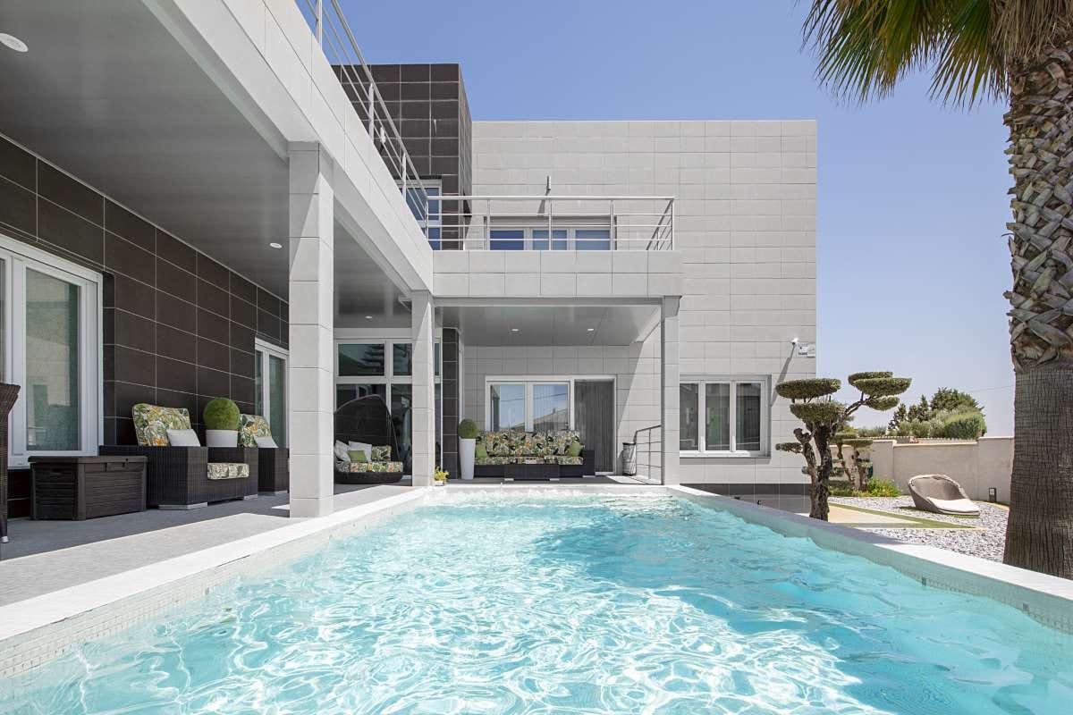Minimalist detached house with pool, palm gardens, and porch rattan sofas