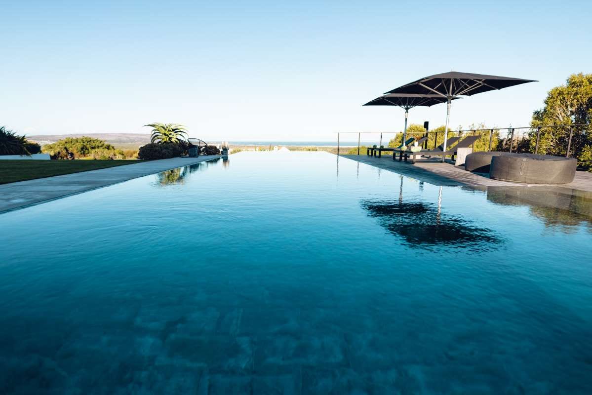 Empty deckchairs and umbrella by a pool with copy space and blue sky