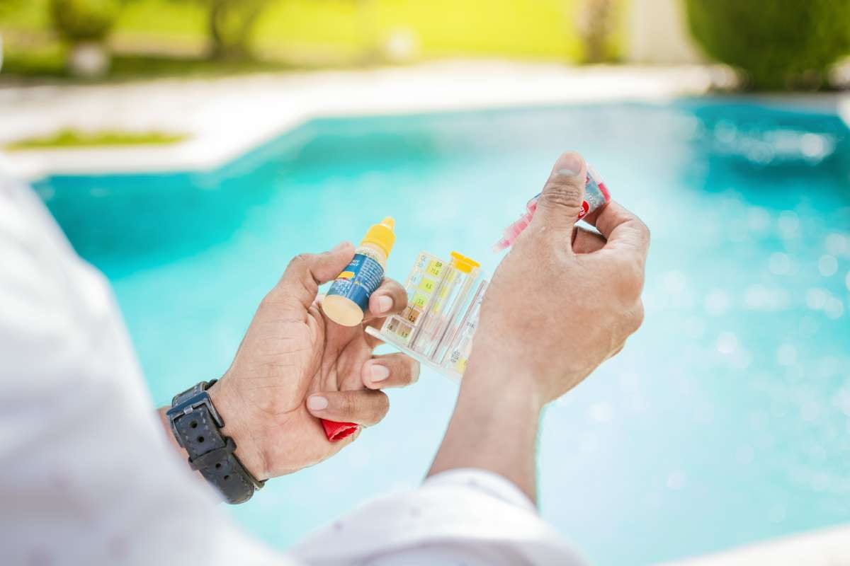 Hand holding a pool chlorine tester with blurred pool background