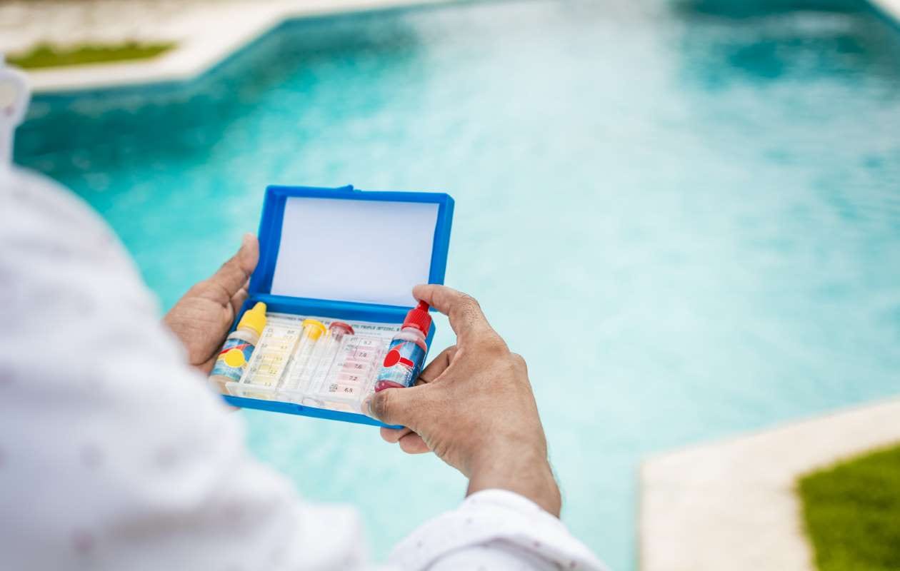 Hand holding pool chlorine tester with blurred pool background