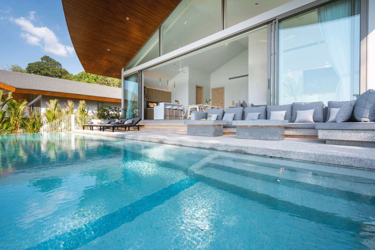 Luxury villa with infinity pool and sun loungers beside modern home exterior