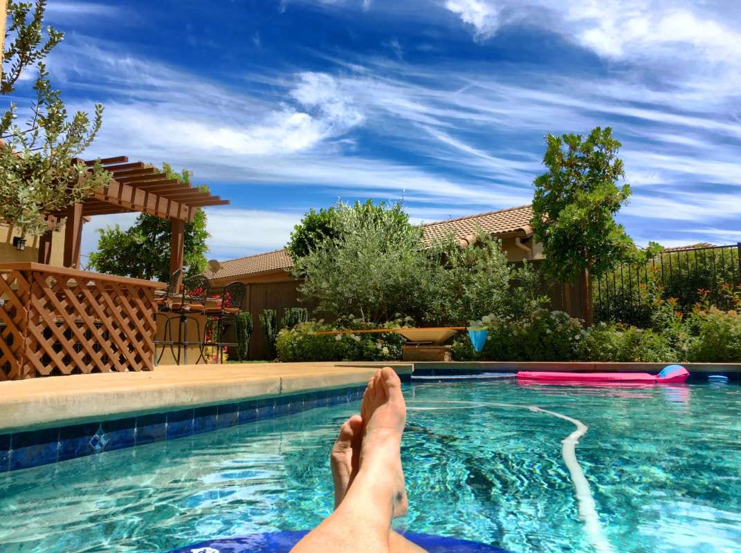 Man relaxing by a swimming pool, suggesting a follow-up conversation during a calm moment