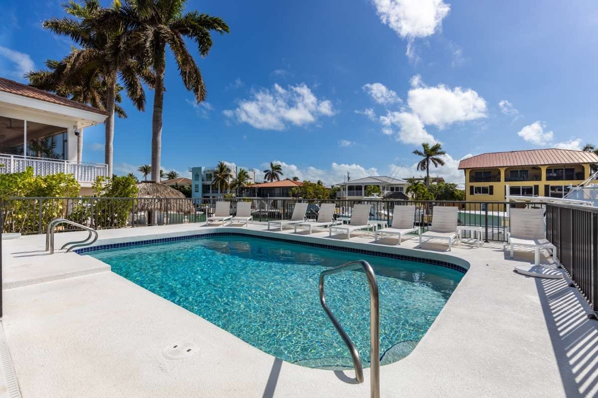 Modern building with pool, chairs, trees, and blue sky landscape