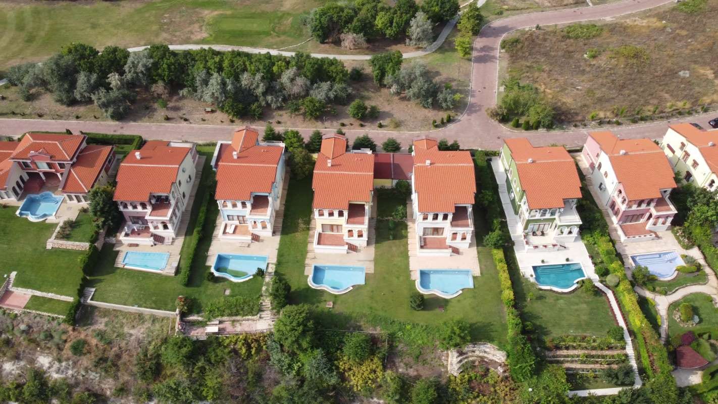 Aerial view of a modern cottage village with luxury homes, pools, and golf courses