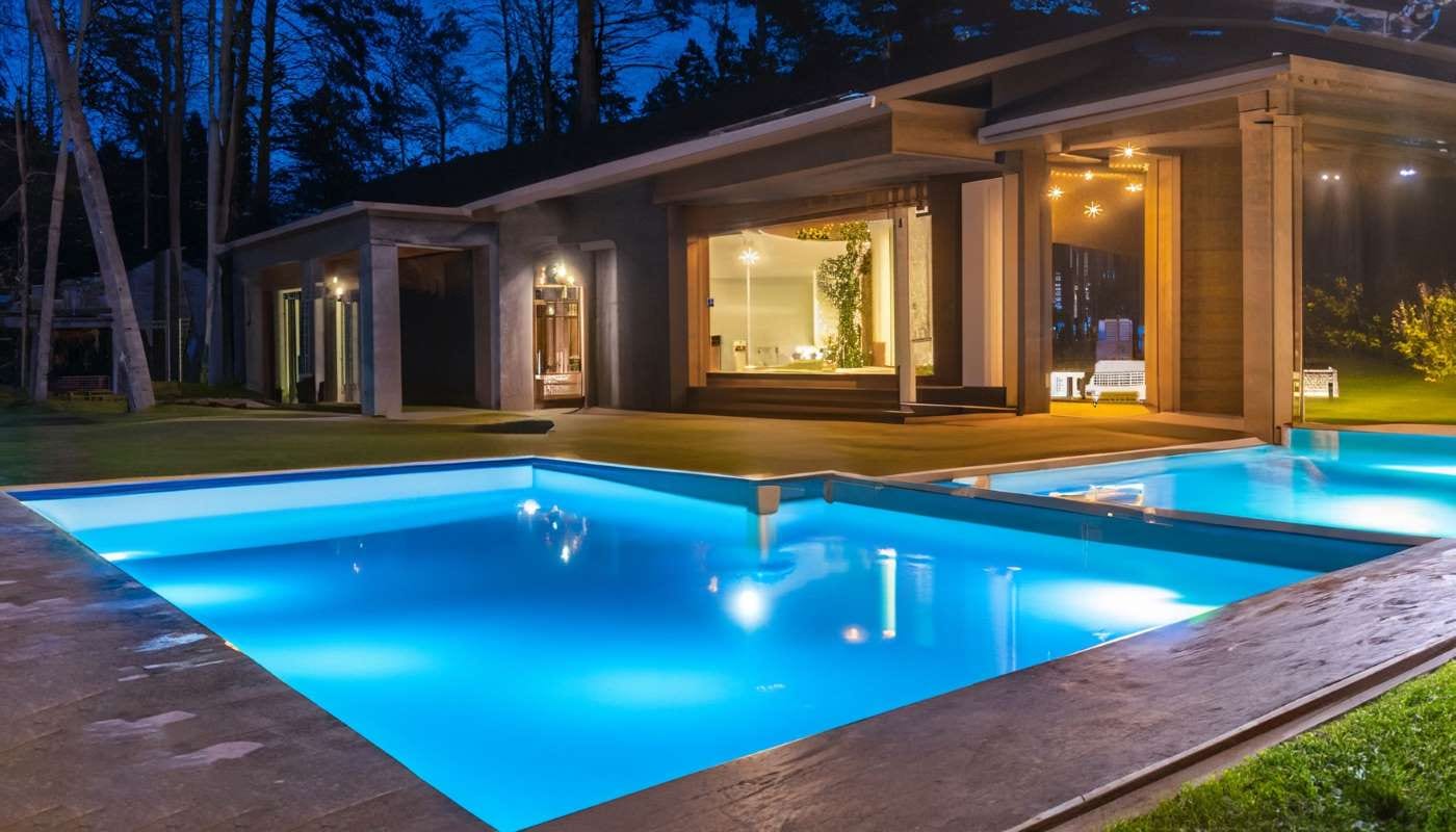Night view of a white house with solar panels and a swimming pool