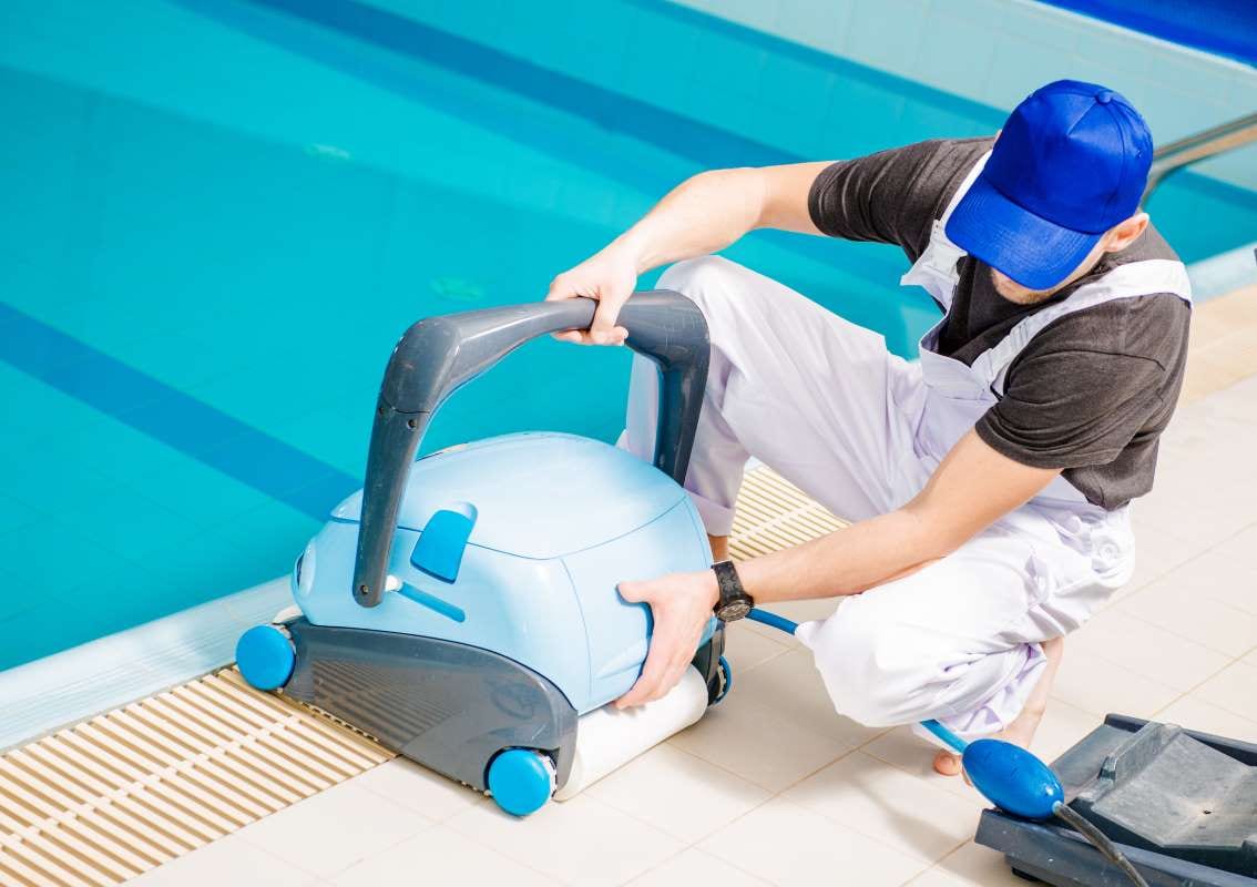 Pool technician using a vacuum cleaner beside swimming pools