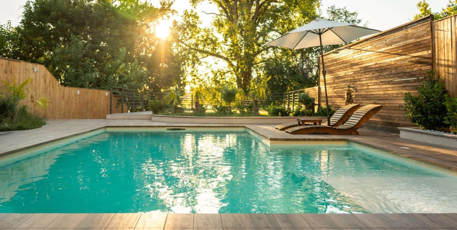 Sunset over a luxury villa pool with wooden lounge chairs and serene opulence