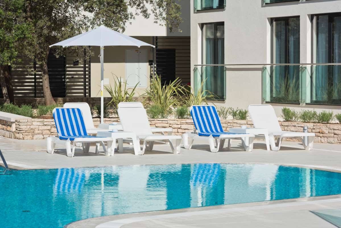 Sunbeds and umbrellas beside a swimming pool on a sunny day